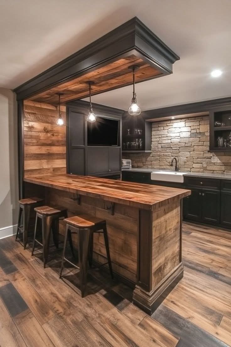 Rustic home bar with a wood counter, stone backsplash, and pendant lighting